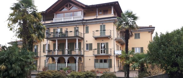 A multi-story hotel with balconies, arched windows, and a sign indicating it is a hotel. - Azalea Hotel (Baveno)
