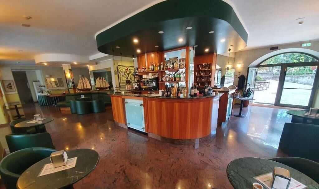 A bar area with a curved counter, seating, and a view of the outdoors.