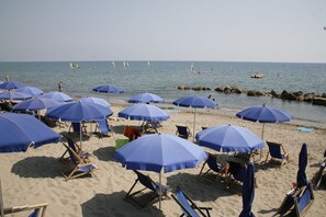 Una playa con varias sombrillas azules y sillas de playa.