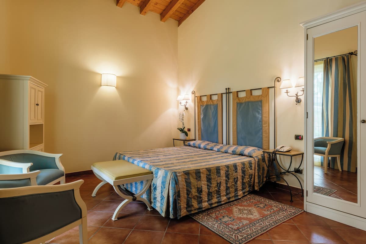 Une chambre à coucher comprenant un lit, une table de chevet, une lampe, une chaise et une armoire.