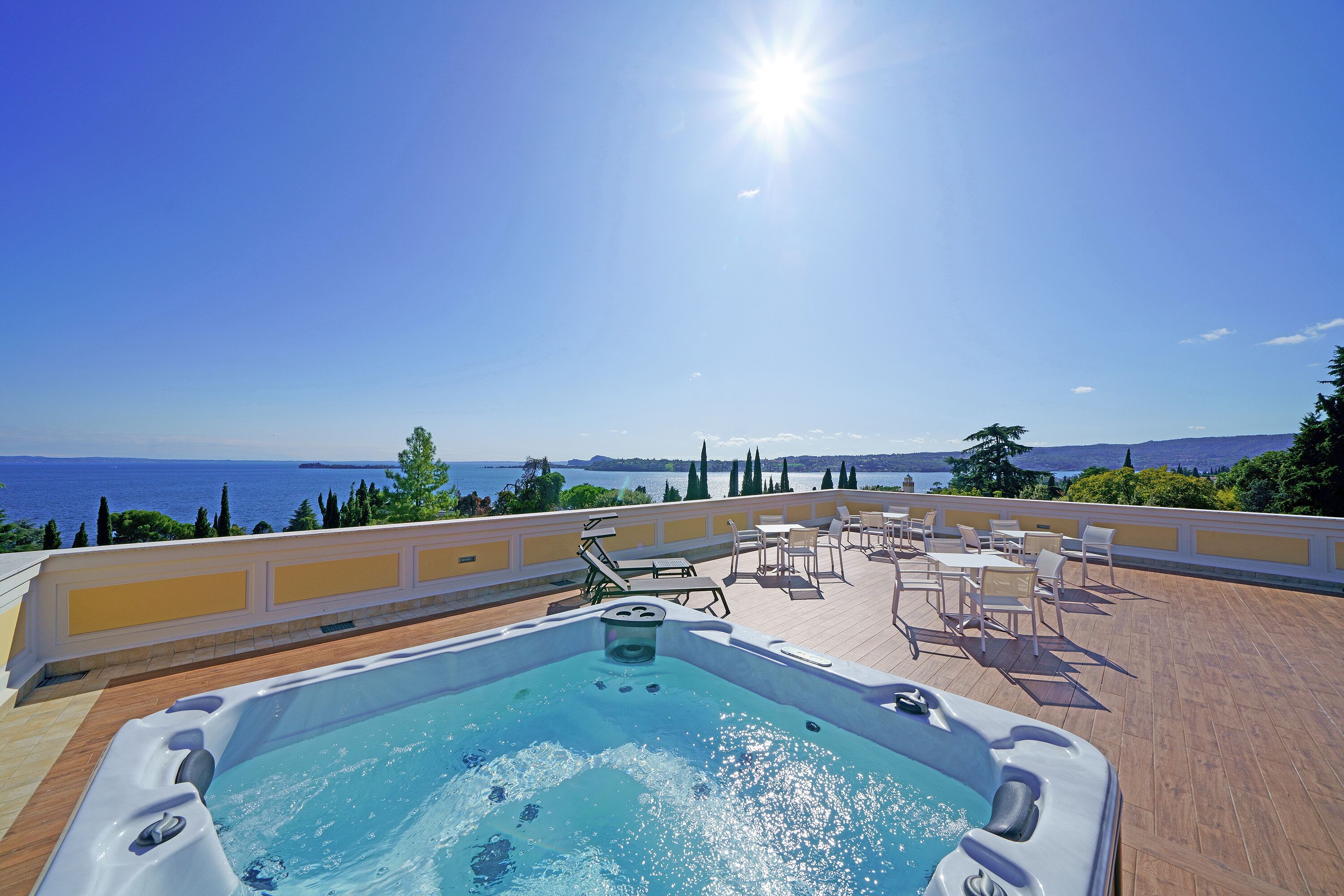 A rooftop pool with a hot tub, outdoor seating, and a view of the sea.