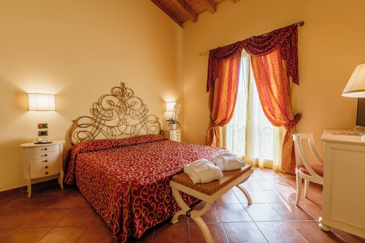Une chambre à coucher avec un lit, une table de chevet, une lampe et une fenêtre avec des rideaux.
