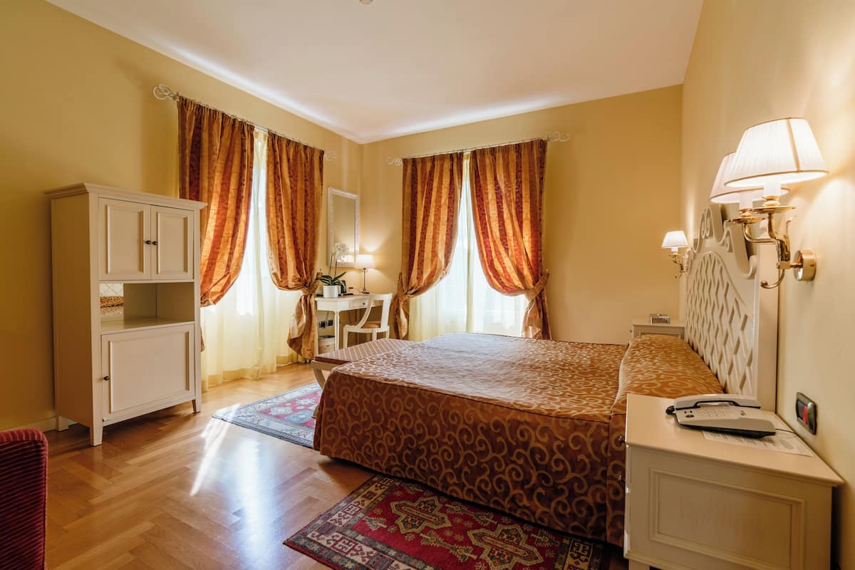 Une chambre d’hôtel comprenant un lit, un bureau, une chaise, une armoire et une table de chevet.
