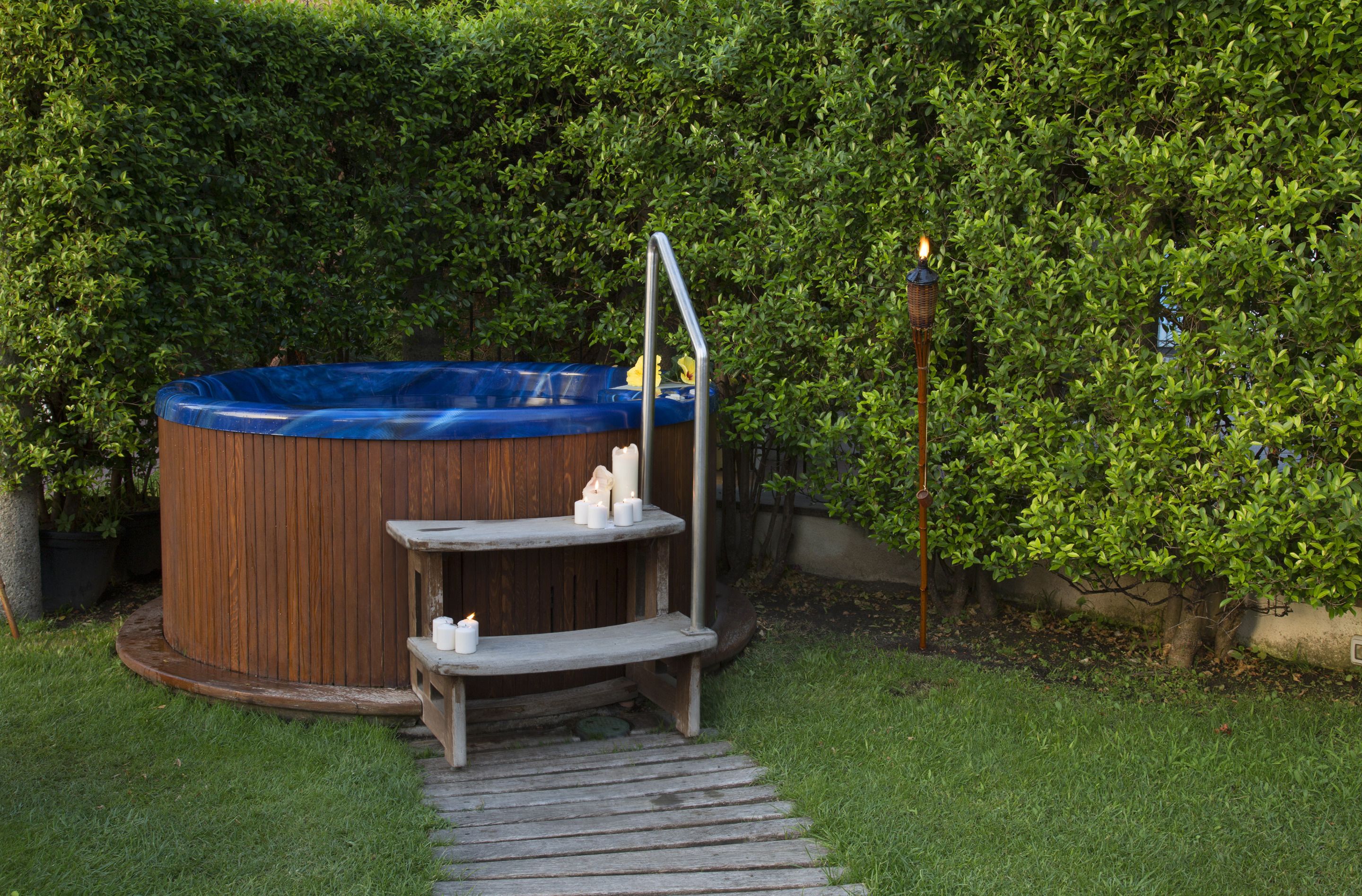Ein Whirlpool mit Holzverkleidung und einer Metallleiter, umgeben von einer Holzterrasse und einer kleinen Stufe.
