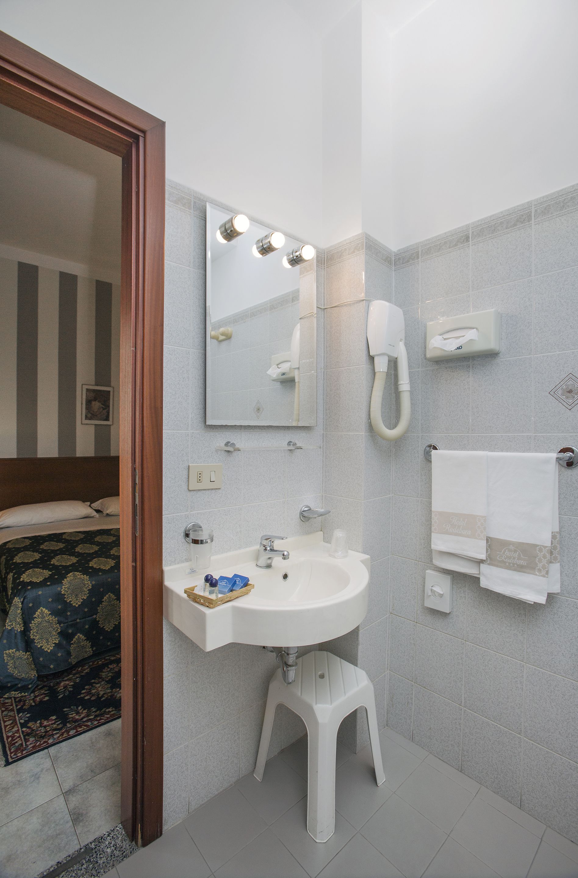 A bathroom with a white sink, a mirror, a hairdryer, and a towel rack.