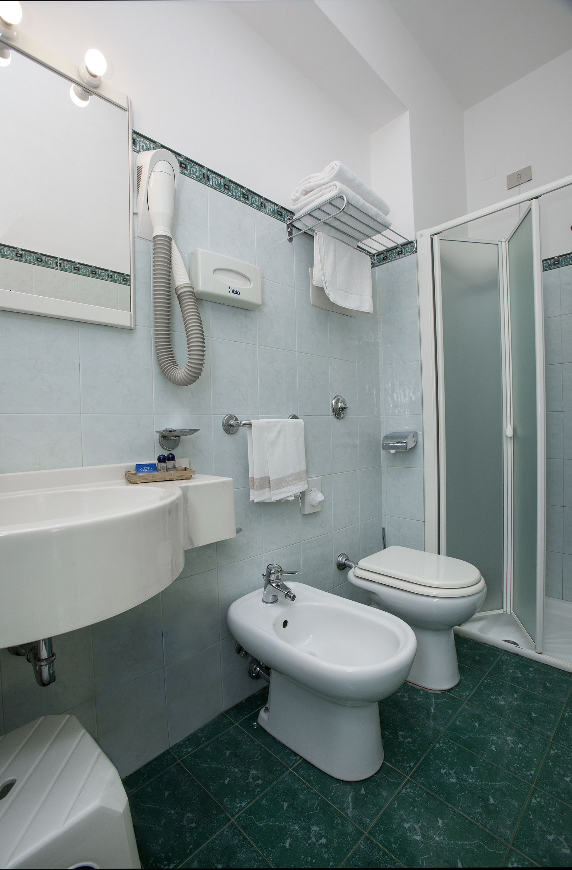 Ein Badezimmer mit Waschbecken, Bidet, Toilette und Duschbereich.