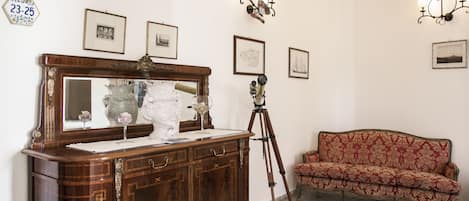 Una habitación con un armario de madera, un trípode y un sofá estampado.