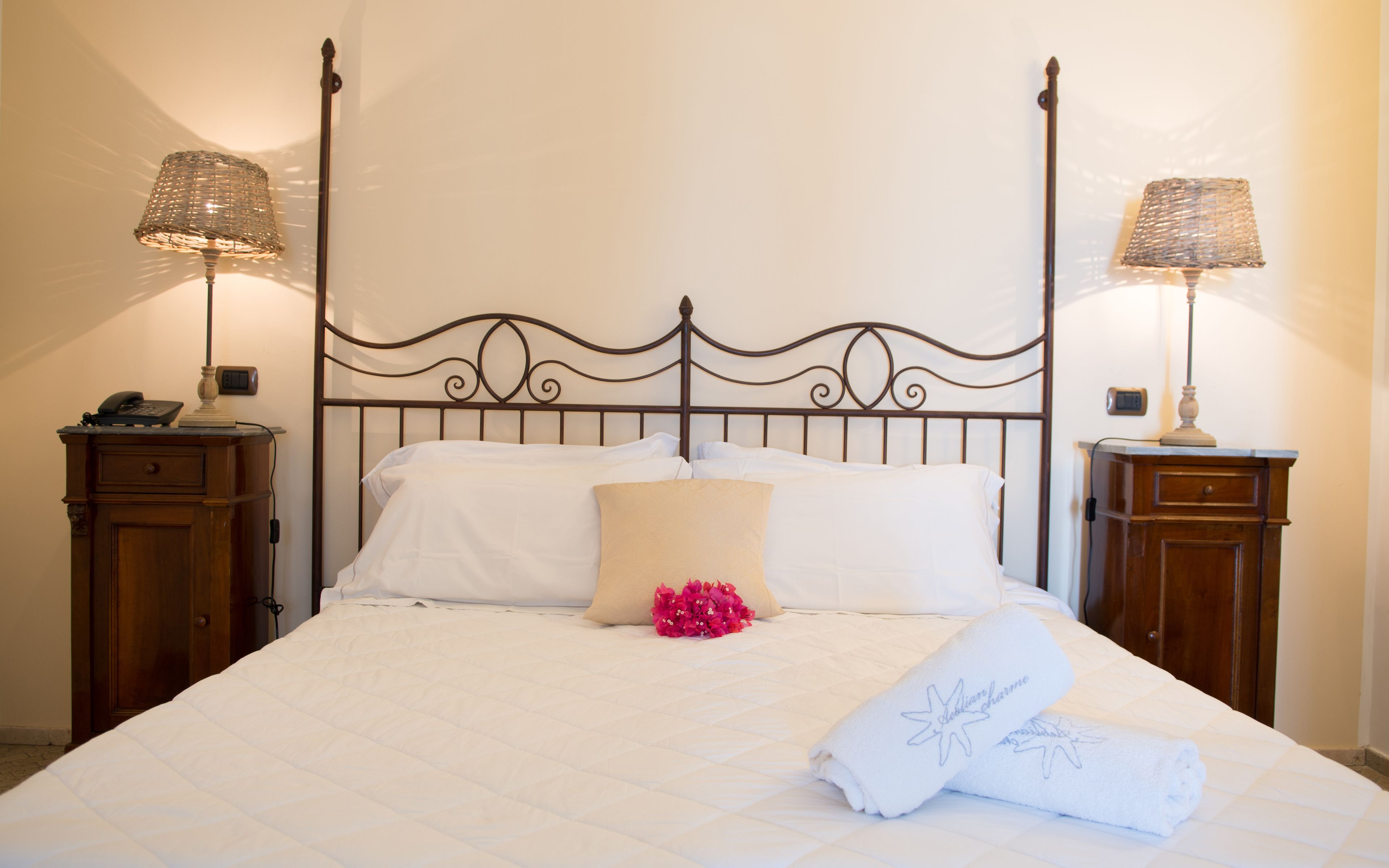 A neatly made bed with white linens, a decorative headboard, and two bedside tables with lamps.