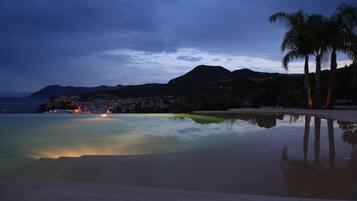 Una playa tranquila con una piscina cristalina que refleja el cielo y palmeras.
