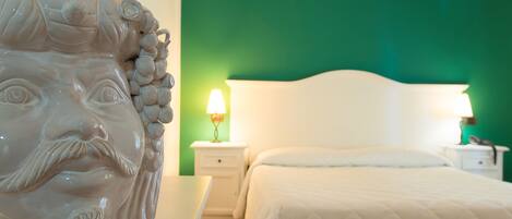Une chambre avec un mur vert, une tête de lit blanche et deux lampes de chevet.