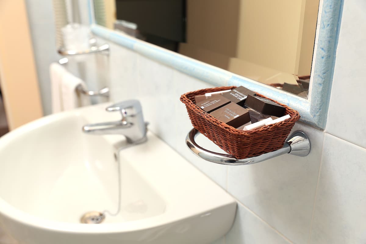 A bathroom sink with a chrome faucet, a wicker basket on the wall, and a mirror above the sink.