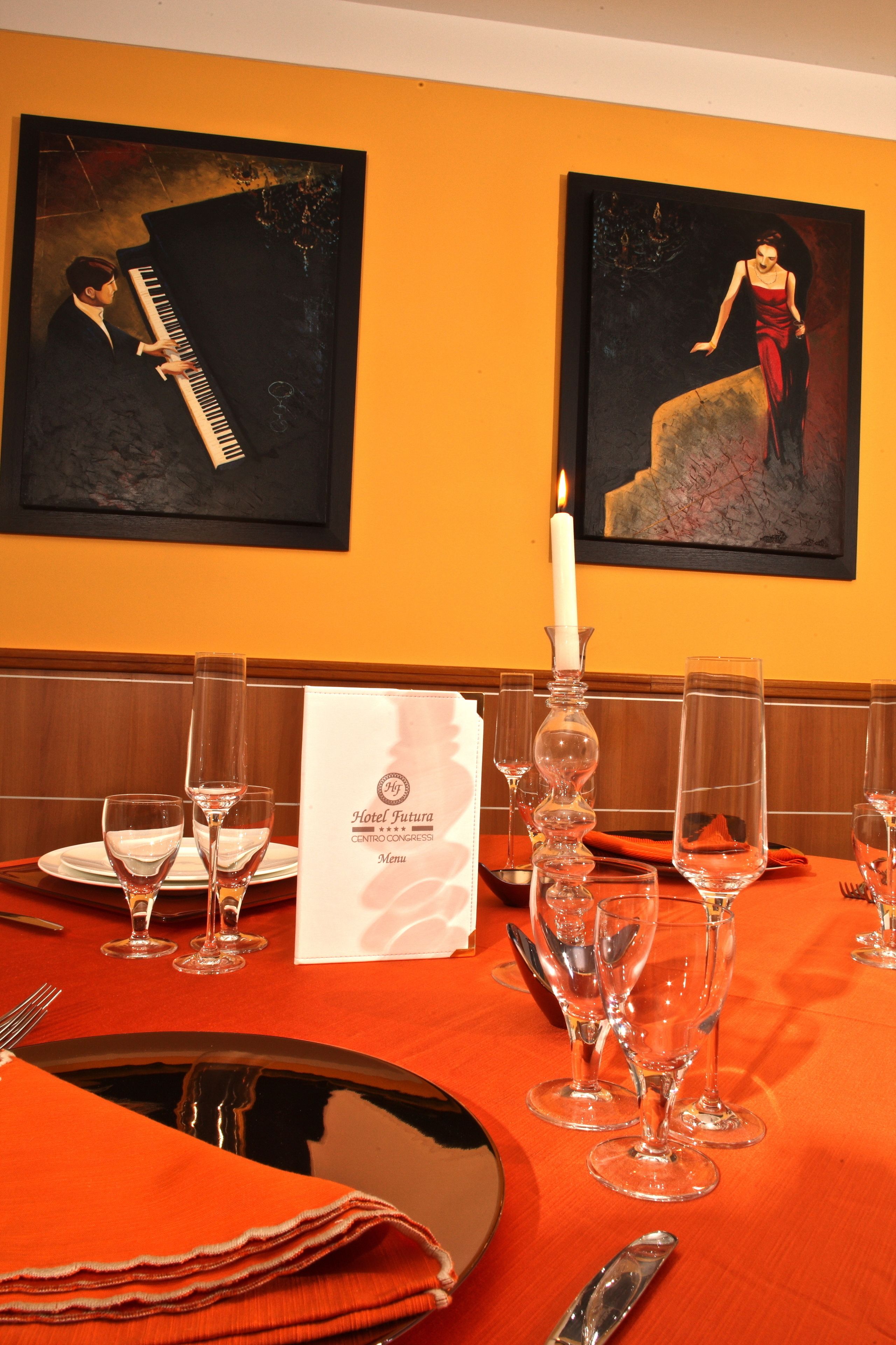 Une table à manger dressée avec des verres à vin, un menu et une bougie.