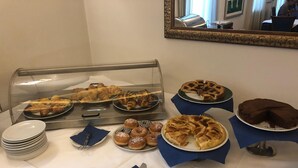 A buffet table with various pastries and desserts, including croissants, donuts, and a chocolate cake. - Hotel Villa Savoia (Turin)