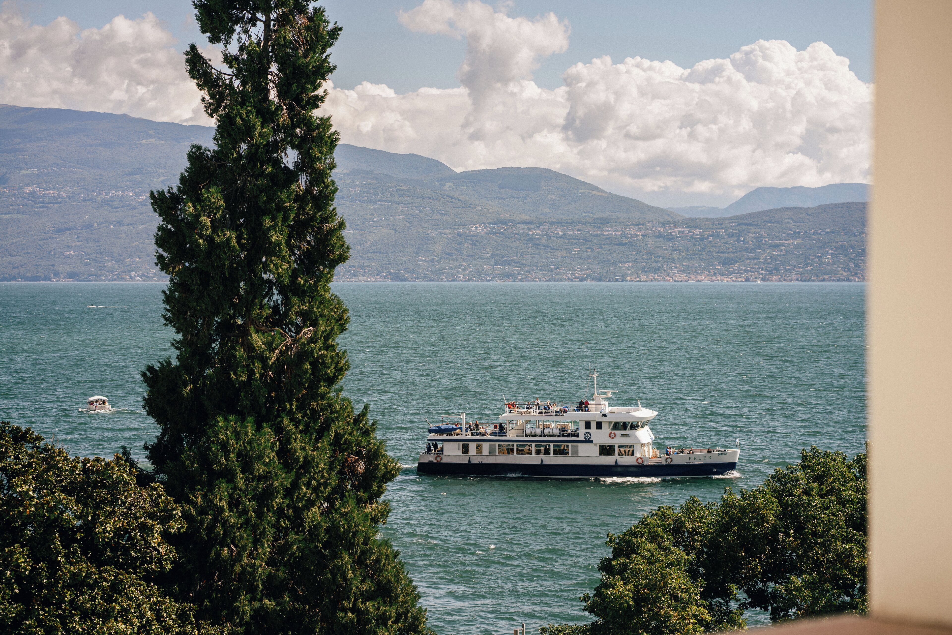 Un barco de ferry en un lago tranquilo con montañas al fondo.