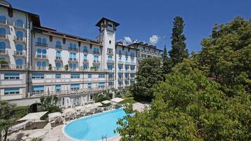A hotel with a large pool, multiple balconies, and lush greenery.