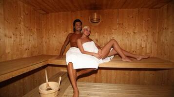 Una sauna con paredes y bancos de madera. En el suelo, un balde de madera y una cuchara para servir.