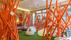 Una habitación con estructuras cilíndricas anaranjadas, una computadora y un piso de césped artificial verde.