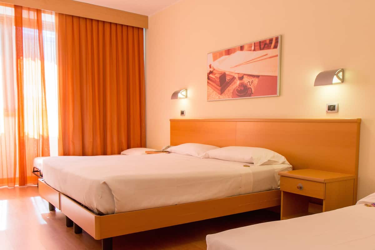 Habitación de hotel con una cama grande, una mesita de noche y una lámpara de pared.