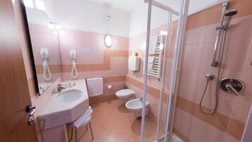 A bathroom with a sink, toilet, bidet, and shower.