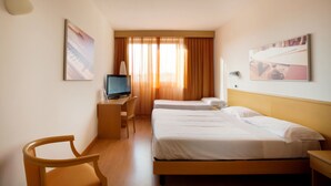 Una habitación de hotel con dos camas, un escritorio con televisión y una silla.