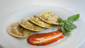 Un plato de ravioles, una rodaja de tomate y hojas de albahaca.