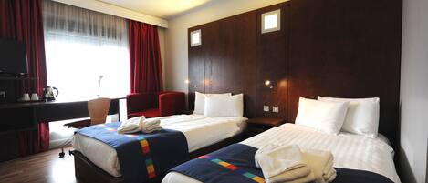 Ein Hotelzimmer mit zwei Betten, einem Schreibtisch und einem Stuhl.