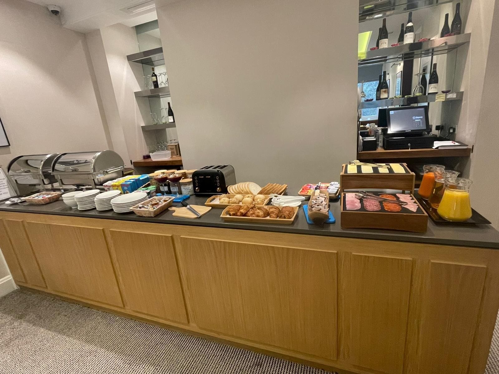 A breakfast buffet with various food items, a coffee machine, and a wine selection.