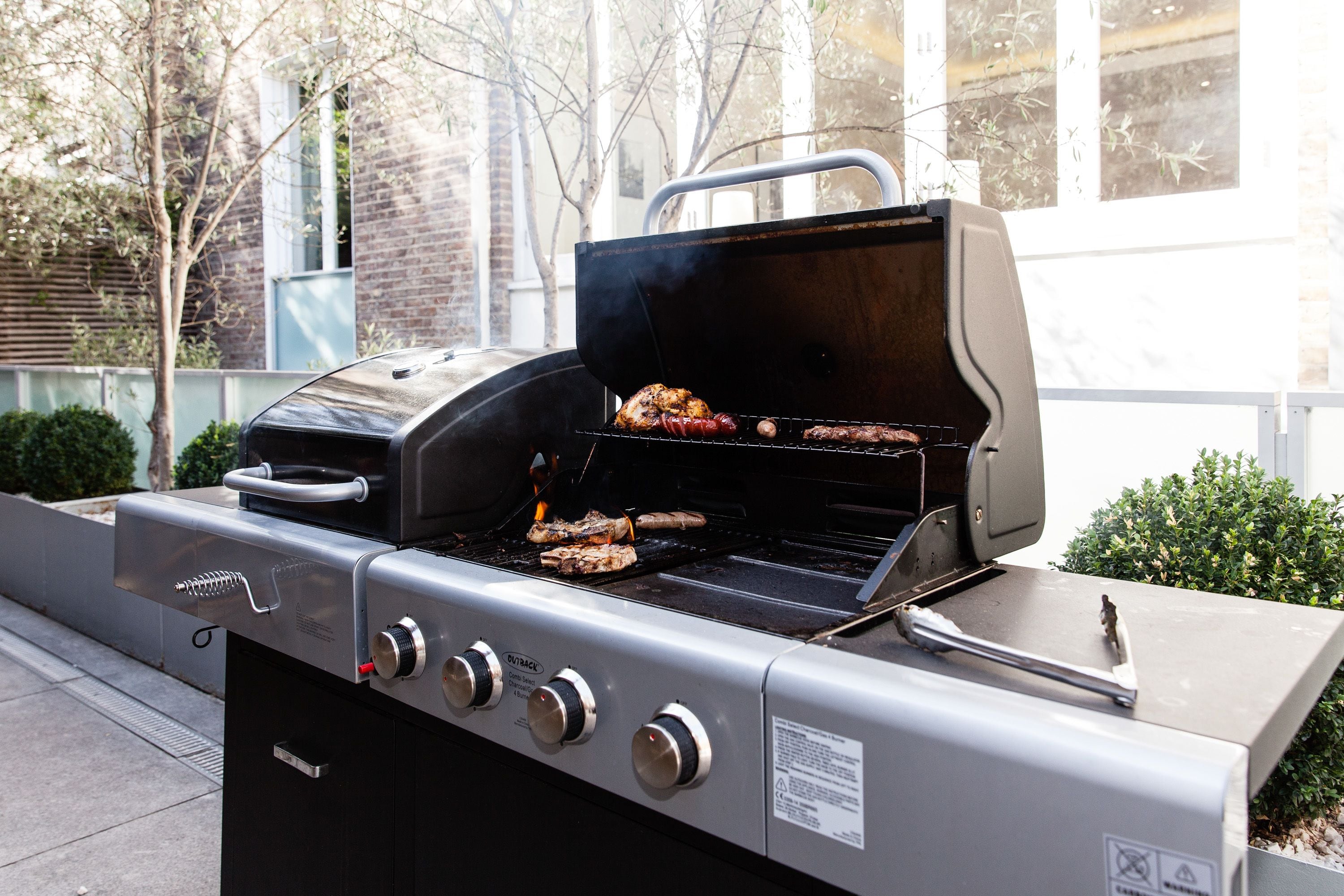 A stainless steel outdoor grill with multiple burners and a side cabinet.