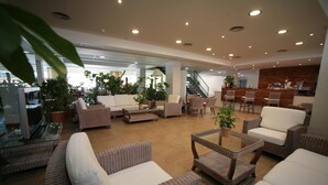A spacious lobby with wicker furniture, potted plants, and a bar area. - Vime Islantilla (Isla Cristina)