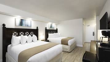 A hotel room with two beds, a desk, and a television.