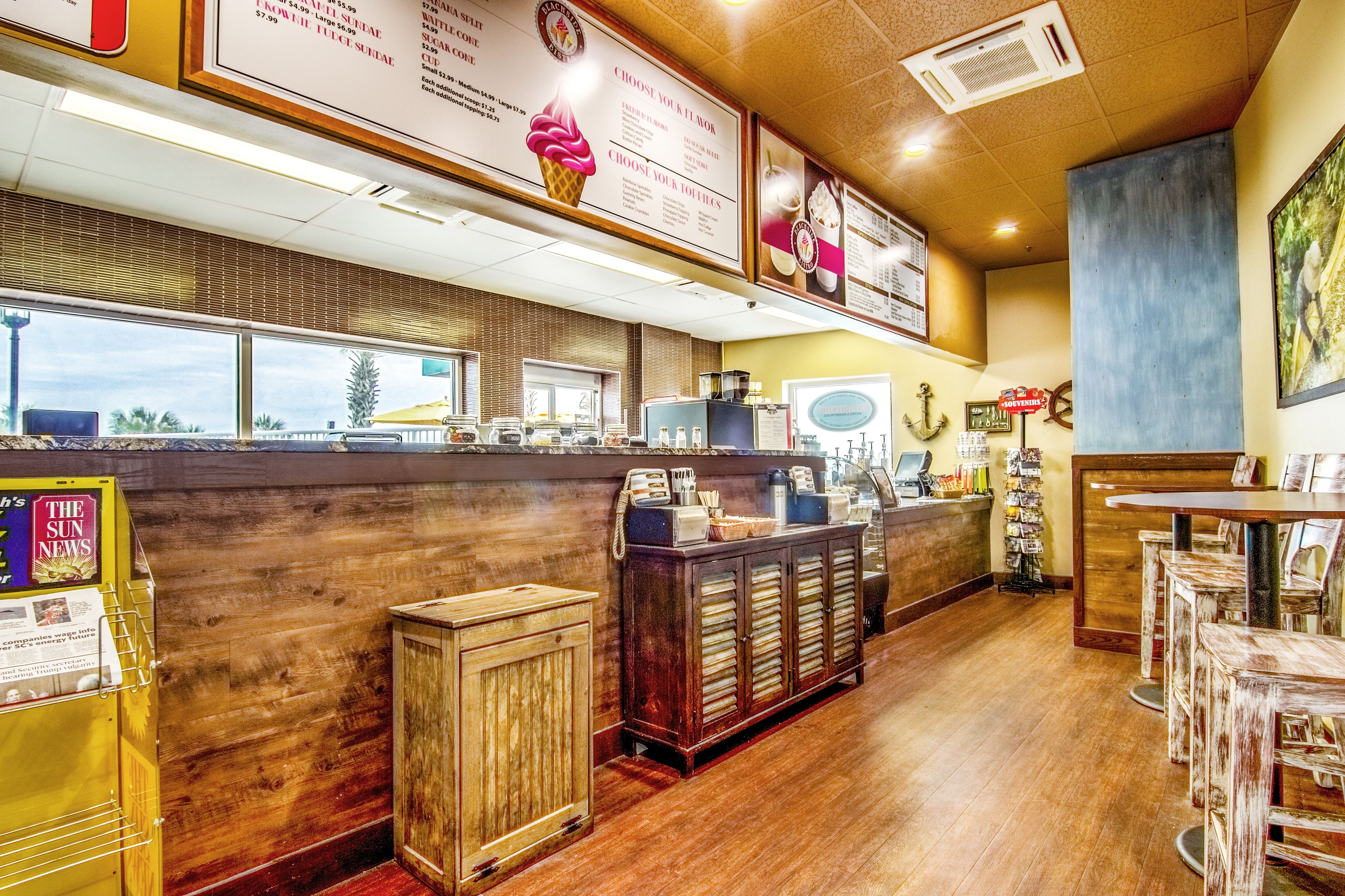 Een lunchroom interieur met een houten toonbank, menuborden en barkrukken.