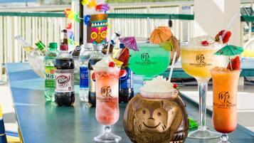 A variety of colorful cocktails on a table with a view of the beach in the background.