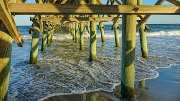 A wooden pier extending into the water with waves lapping at its base.