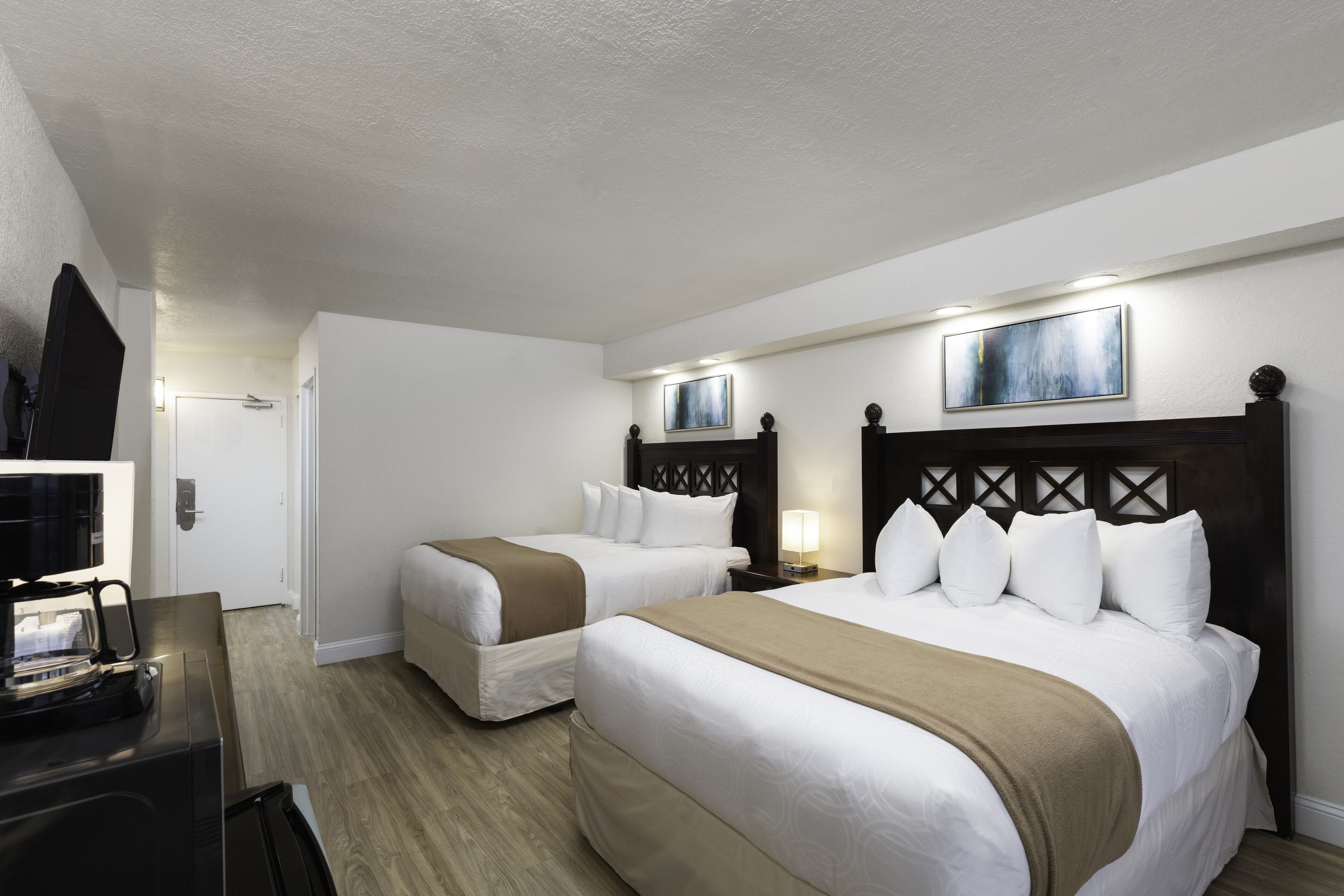 A hotel room with two beds, a TV, and a coffee maker.