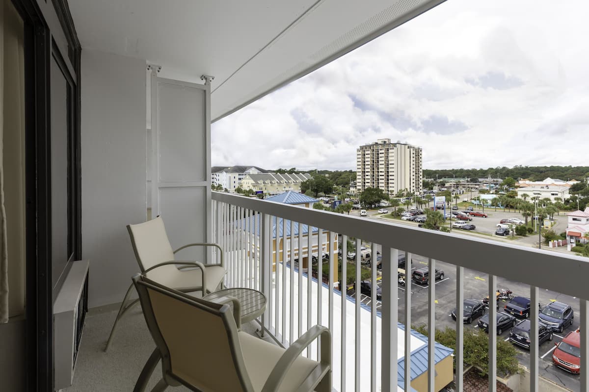 A balcony with a view of a parking lot and buildings.