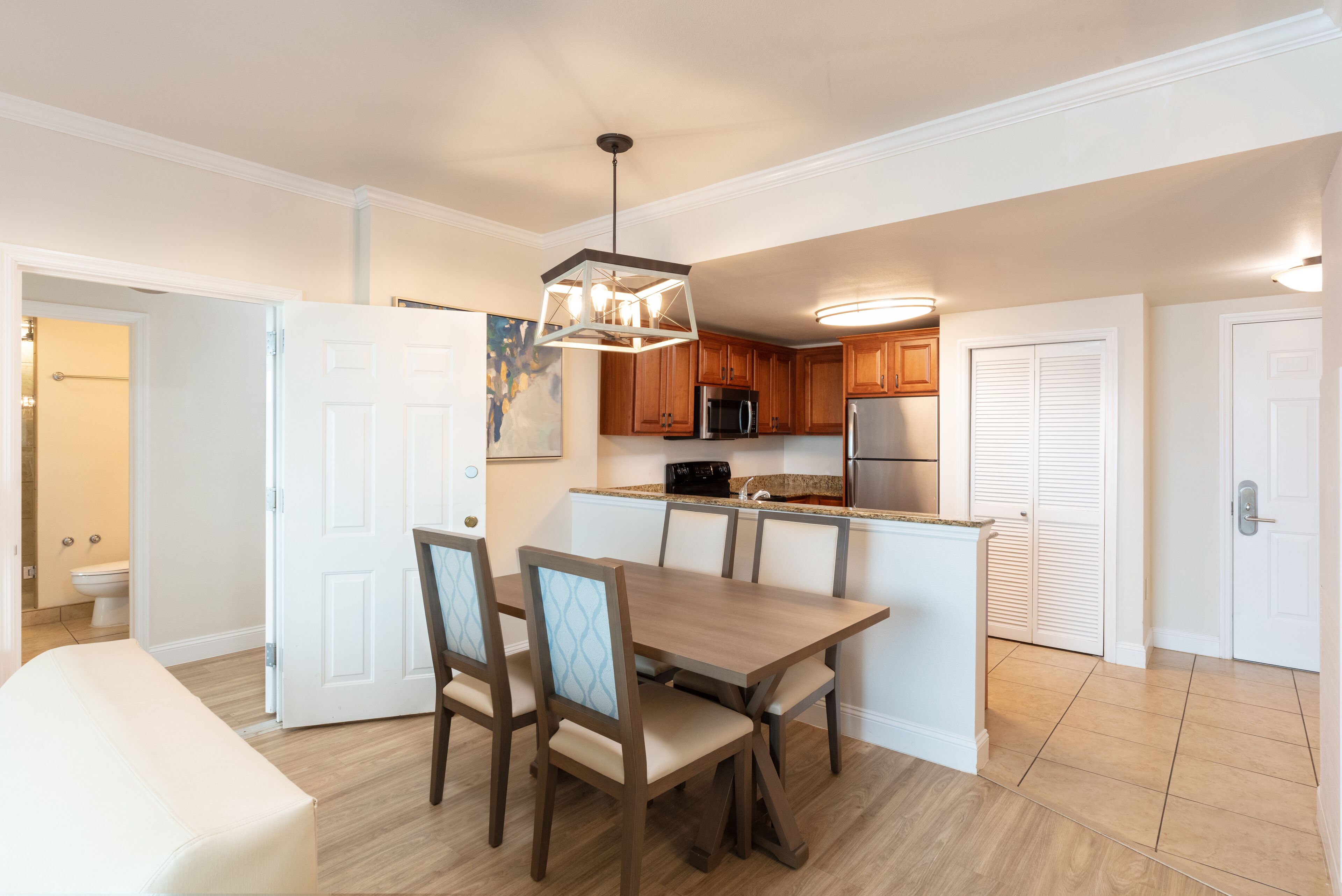 A modern kitchen with wooden cabinets, a central island, and a dining area with a table and chairs.