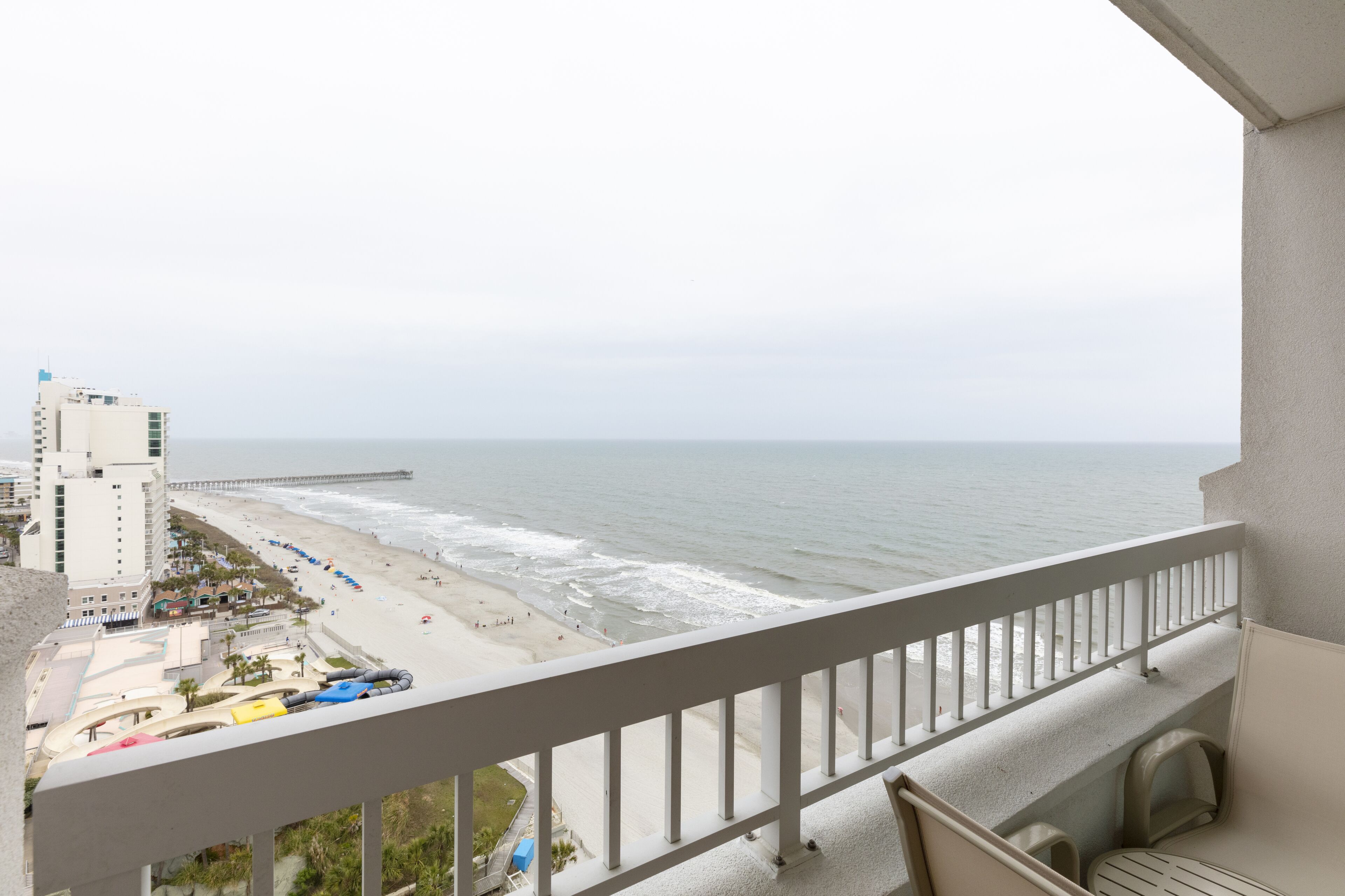 A balcony with a view of the beach and ocean.