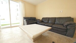 Una sala de estar con un sofá color beige, un sillón más pequeño y una mesa de centro.