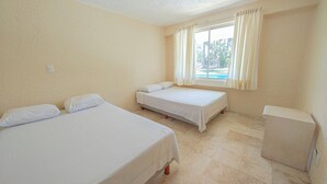 Una habitación con dos camas individuales, una ventana con cortinas y un escritorio pequeño.