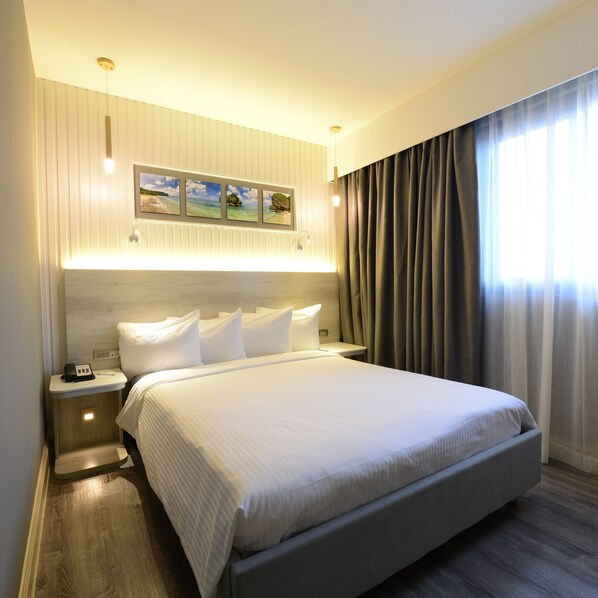 Une chambre d’hôtel moderne avec un grand lit, une table de chevet avec un téléphone et un tableau accroché au mur.
