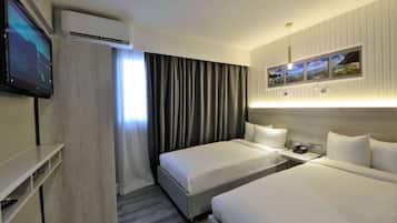A hotel room with two beds, a TV, an air conditioner, and a painting on the wall.