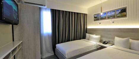 A hotel room with two beds, a TV, an air conditioner, and a painting on the wall.