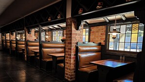 A row of booths with brick pillars and wooden tables, each booth has a window with a view.