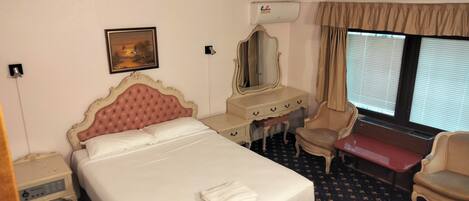 Una habitación de hotel con una cama grande, un escritorio, una silla y una ventana con persianas.