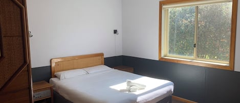 Una camera da letto con un letto, un comodino, una finestra e una porta.