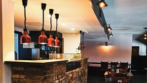 A restaurant with brick walls, wooden tables, and hanging pendant lights.