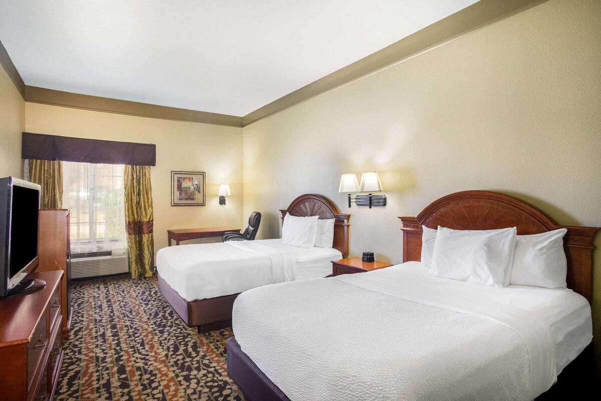 Una habitación de hotel con dos camas, televisión, escritorio y silla.