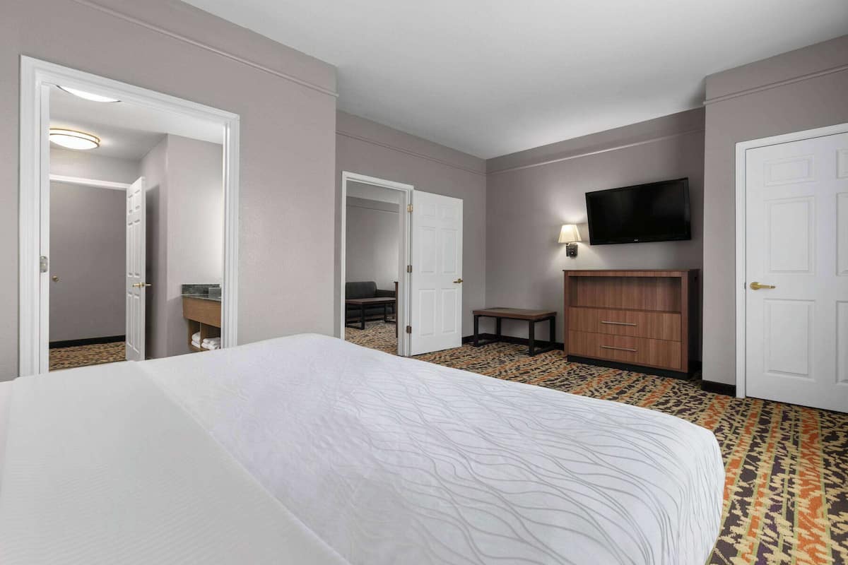 A hotel room with a large bed, a television mounted on the wall, a desk, and a wardrobe.