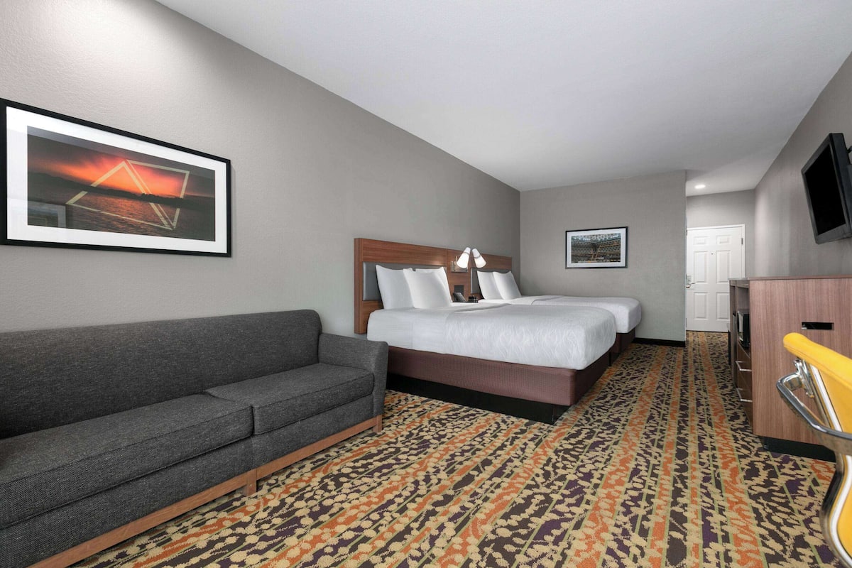 A hotel room with a bed, a sofa, a TV, and a patterned carpet.