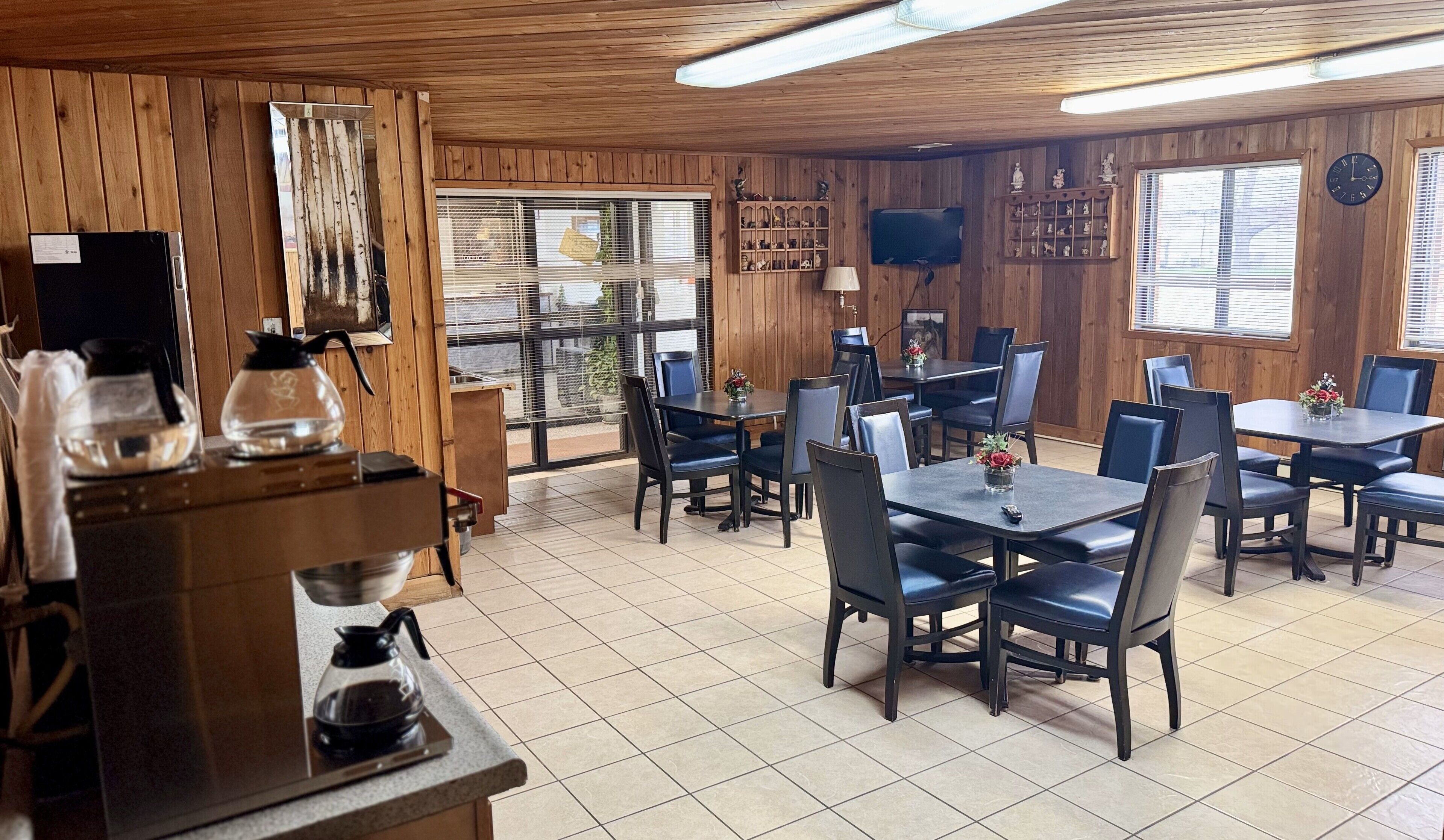 A restaurant with wooden walls, tiled flooring, and tables with chairs.